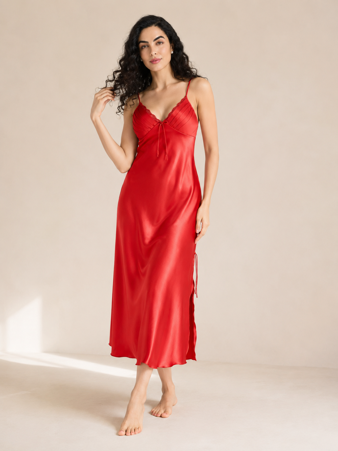 Model wearing scarlet red satin midi slip nightgown in warm studio light