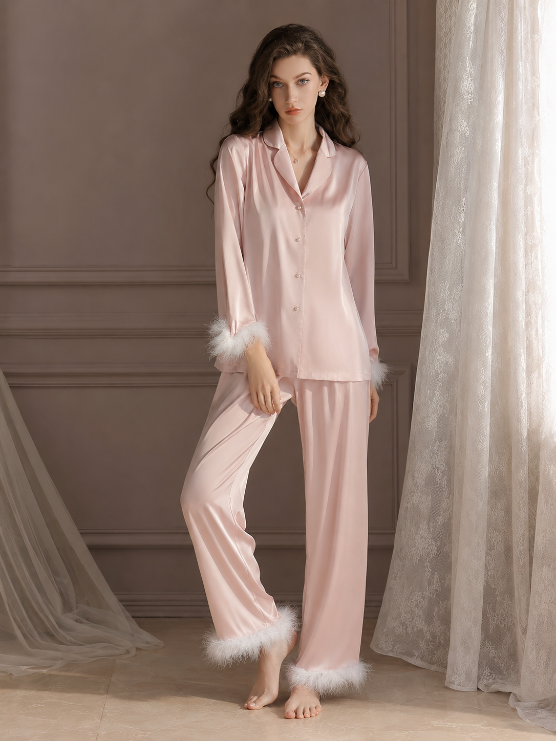 Woman wearing blush pink feather trim satin pajama set with lapel collar and pearl-style buttons