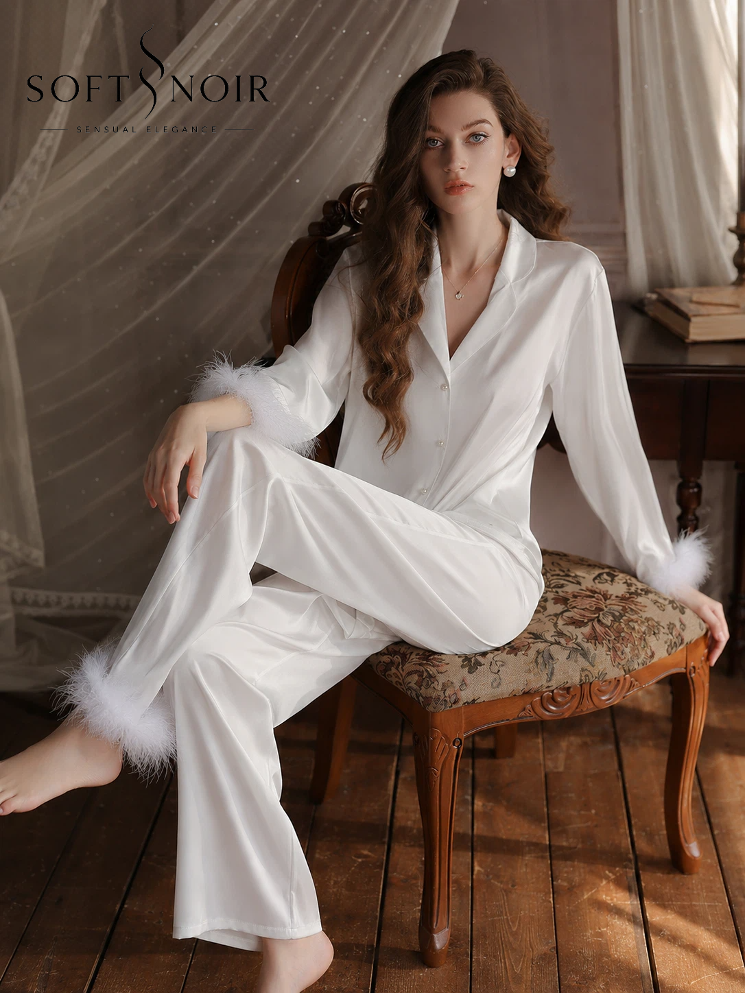 Woman wearing white satin pajama set with feather trim cuffs and wide-leg pants